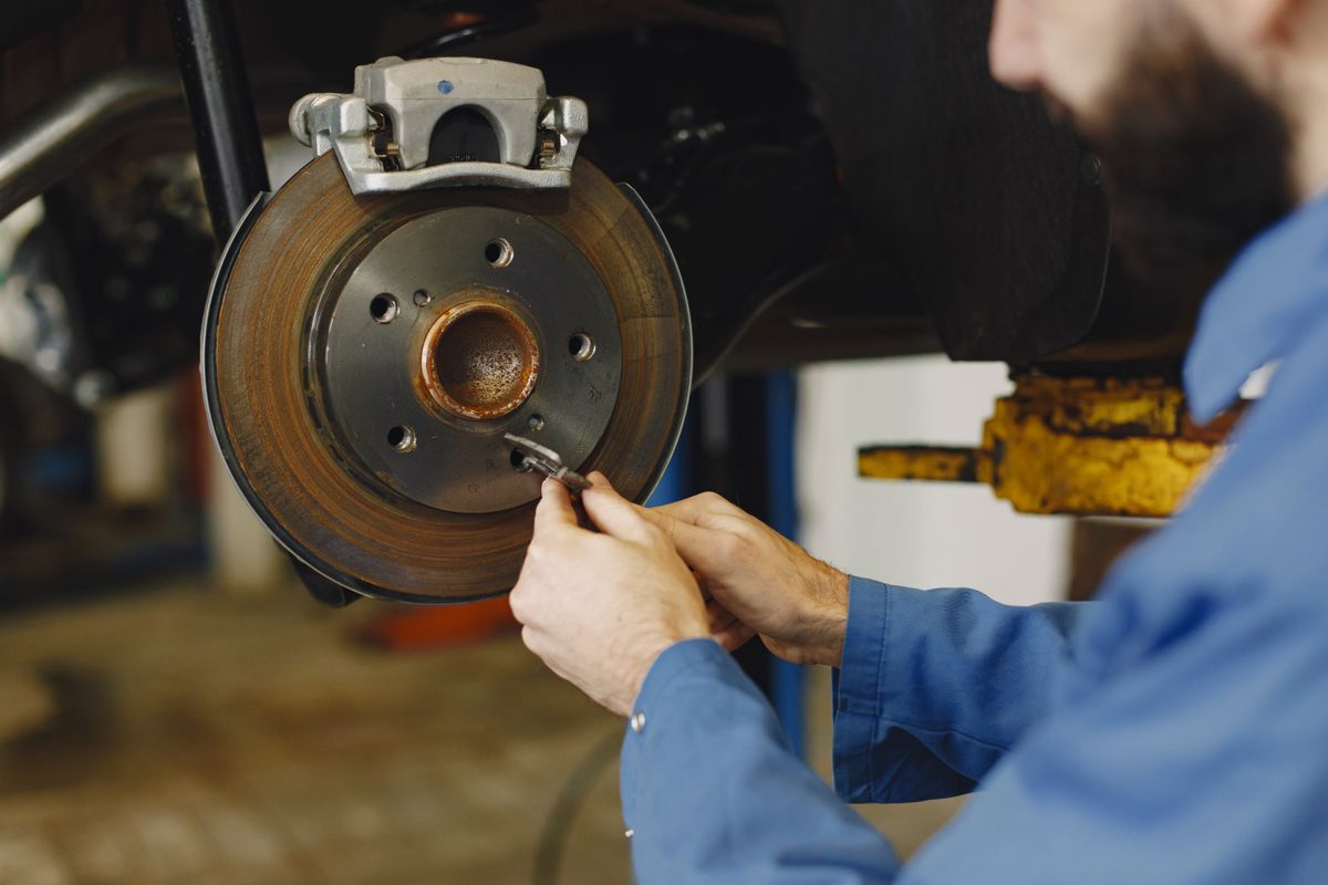 Mechanic inspecting a vehicle brake disc and caliper