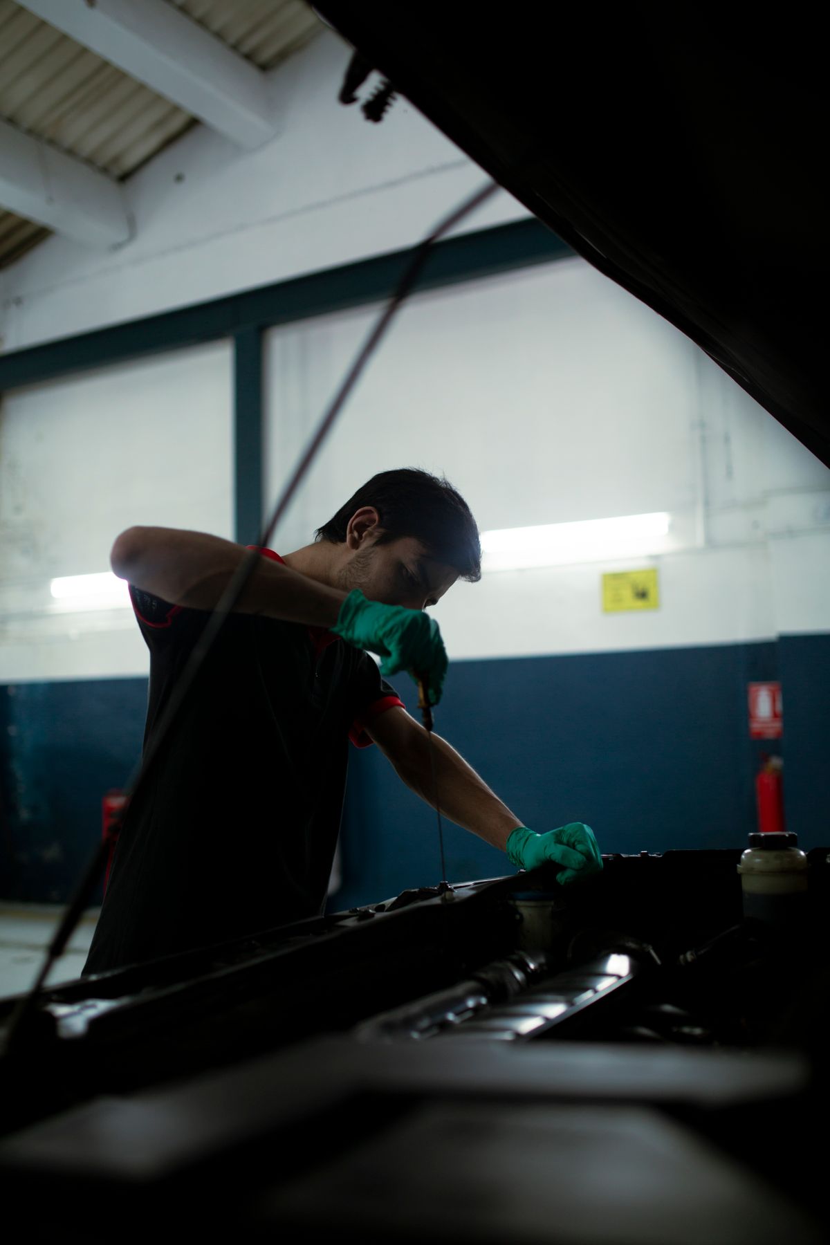 Technician performing routine maintenance under the hood of a vehicle
