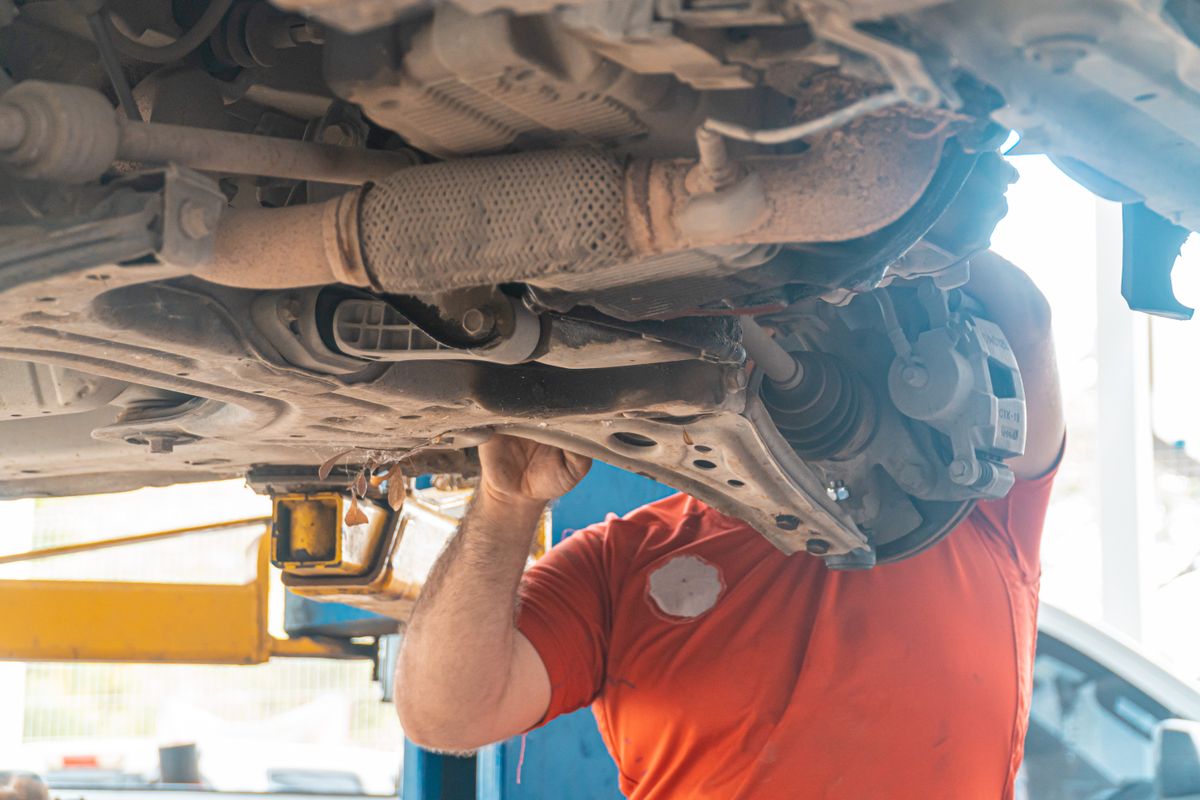 Mechanic inspecting steering and suspension components under a vehicle